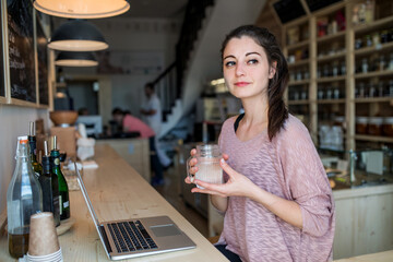 Beautiful woman working remotely in small local bistro. Female business owner.