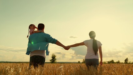 Happy family of farmers with child, are walking on wheat field. Slow motion. Mom, dad, child walk...