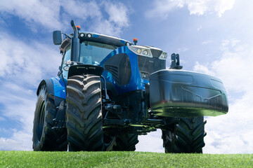 Modern blue agricultural tractor on a background of blue sky.