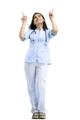 A female doctor, full-length, on a white background, points up