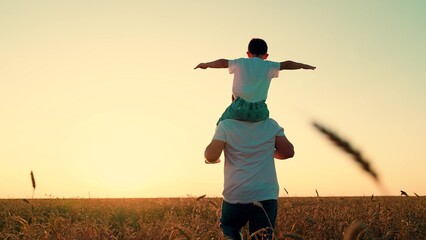 Little kid superhero imagines soaring through sky at sunset. Loving father runs with playful son on...
