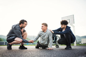 Disabled young man exercising with his supportive friends. Male friendship.