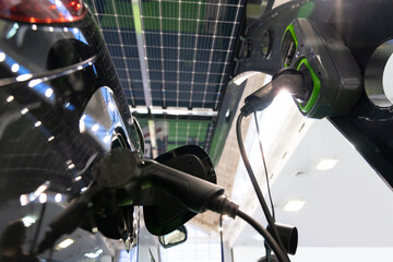 Electric car is charged from a charging station that takes energy from solar panels. Close up..