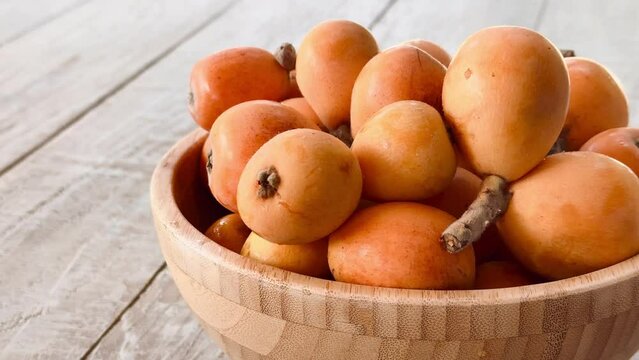 Orange loquats in the bowl on the table just harvested.
