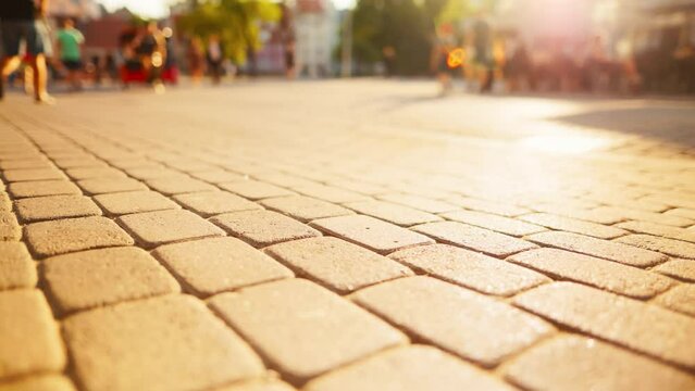 In the bright sunlight, a paved street is bustling with blurred people in the background