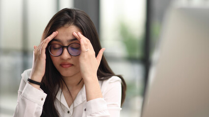 Beautiful portrait of a young woman and female student, while working on her computer or laptop at the office table.