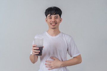 Handsome young man drinks soda and holding plastic cup and soda bottle.