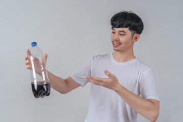 Handsome young man drinks soda and holding plastic cup and soda bottle.