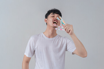 Handsome young man holding several colorful toothbrushes.