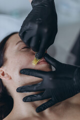 Removing hair above upper lip of young woman in salon. shugaring depilation.