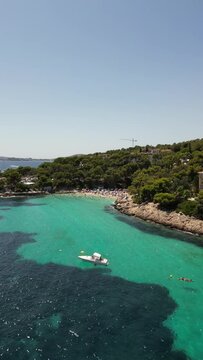 Playa illetas with clear turquoise waters and sunbathers on the beach, mallorca, spain, aerial view