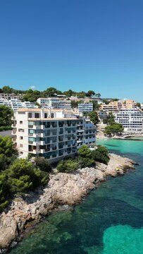 Playa illetas with clear turquoise waters and sunbathers on the beach, mallorca, spain, aerial view
