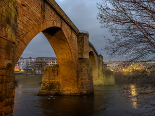 Obraz premium Historic Stone Bridge Over River at Dusk