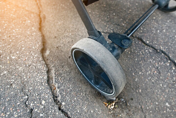 Stroller wheel stuck in hole on an asphalt road, illustrating  hazards of surface depressions and...