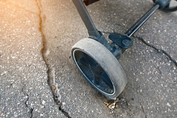 Stroller wheel stuck in hole on an asphalt road, illustrating  hazards of surface depressions and the necessity for timely pavement repair