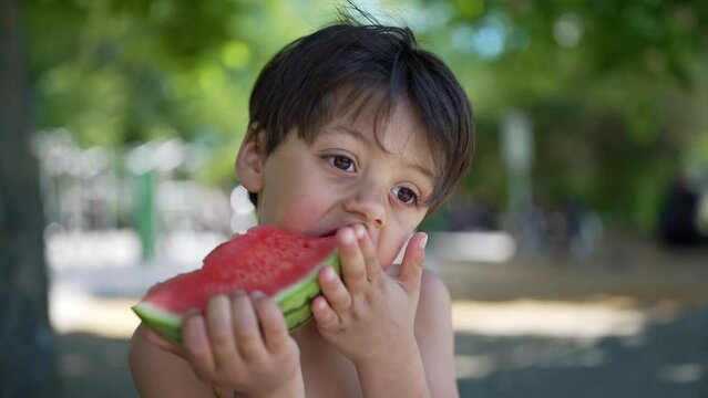 Close-up of young boy eating watermelon slice, savoring a refreshing summer snack, shirtless with messy face, enjoying a sunny day outdoors, healthy and natural hydration, playful moment