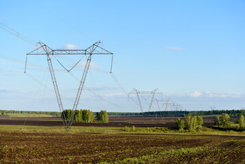 A high-voltage power line on the background of a rural field. Landscape in the village and electrical wiring.