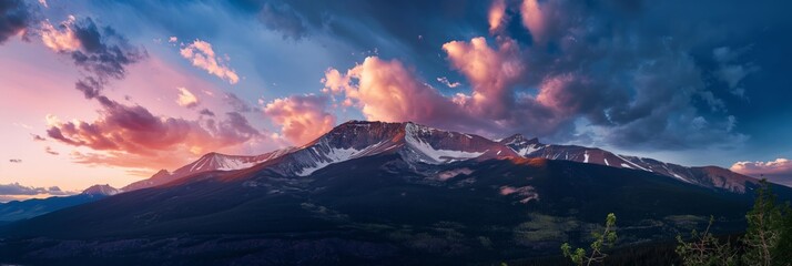 Majestic panoramic view of a mountain range under a dramatic sky at dusk