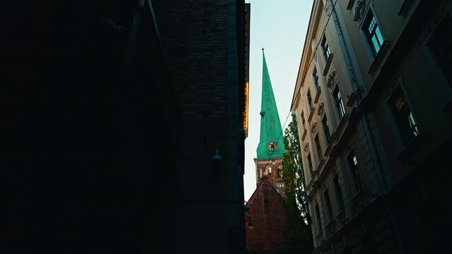 Capture a narrow alley with a church steeple and a magnificent sunset, creating captivating scenery