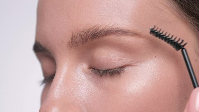 The make-up artist combs the eyebrows and makes the styling of the eyebrows with a gel.