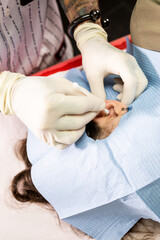 Fototapeta premium An unrecognizable professional performs a piercing on a woman's ear.The man cleans the area of ​​the ear where the piercing is done.Concept of doing piercing.