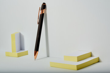 Elegant ball point pen resting up against a white background with some note pads.