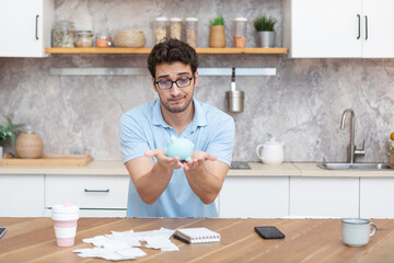 Close up of unhappy man sitting at the table, stressed and confused by calculate expense from...