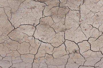 Close-up top view of dry brown cracked clay land surface in a summer day. Abstract weather background. Soft focus. Copy space. Drought and climate change theme.