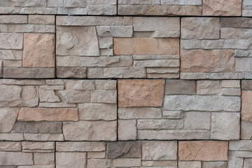 Close-up view of textured beige building wall surface covered with stone shaped tiles. Abstract construction industry background. Copy space. Soft focus. Decor materials theme.