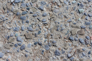Close-up top view of textured rough gray rural road surface nade from concrete and gavel stones. Soft focus. Abstract building background. Copy space. Road construction theme.