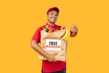 Delivery man wearing a red shirt is seen holding a bag of food, showing thumb up. He appears to be...