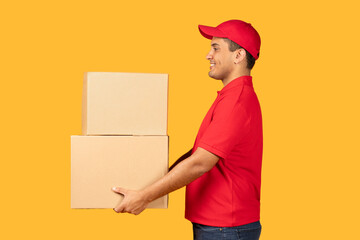 A delivery guy in a red uniform and cap is holding two cardboard boxes, showing a side profile against a bright yellow backdrop.