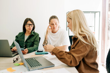 Female colleagues discussing social media marketing strategy at a business meeting.