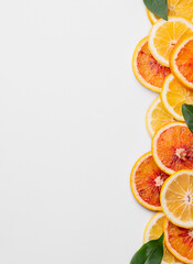 Juicy slices of lemons, blood oranges and  leaves on a light isolated background. Flat lay of...