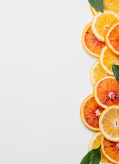 Juicy slices of lemons, blood oranges and  leaves on a light isolated background. Flat lay of...
