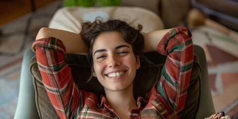Obraz premium Woman lying back on a couch, relaxing with her arms raised behind her head as she looks upwards