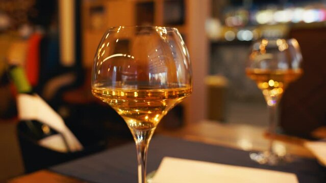 An elegant wine glass is elegantly placed in a fine dining setup, along with an orange wine