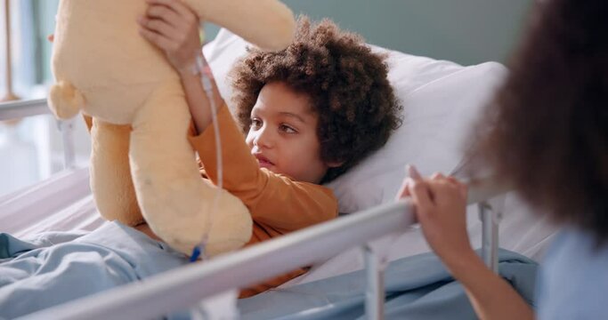 Boy, hospital and teddy in bed with smile, recovery and help for patient with mom on bedside for support. Treatment, iv drip and hand for healthcare, toy and rehabilitation in pediatric care