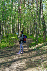 Obraz premium Portrait and wide shoot of young woman looking on the map while crossing hiking trail in spring forest