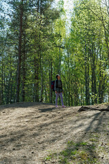 Obraz premium Woman stopped on a hill and looking up on trees while doing hike in spring forest