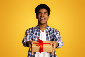 Happy Guy Offering Craft Gift Box Wrapped with Red Ribbon and Bow to Camera