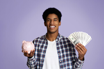 Saving Money Concept. Happy Guy Holding Bunch of Money and Piggybank on Pink Background