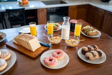 Breakfast food table. Festive brunch set, meal variety with donuts, croissants, sandwiches, milk...