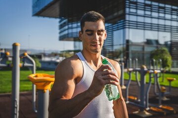 Fototapeta premium man young male athlete hold bottle of water drink training outdoor