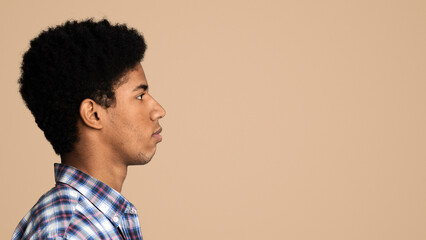Profile portrait of afro teen guy over white background, looking at free space