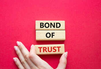 Bond of trust symbol. Wooden blocks with words Bond of trust. Beautiful red background. Businessman...