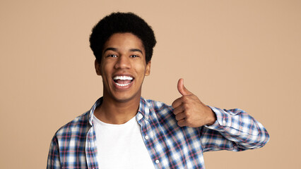 Happy afro-american guy showing thumb up gesture and smiling over white background