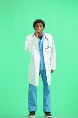 The doctor, in full height, on a green background, tells a secret