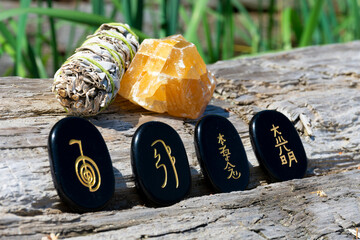 An image of four healing spiritual symbols with an orange calcite crystal and white sage smudge...