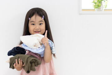 洗濯物を持ちピースする笑顔の女の子（3歳、日本人）